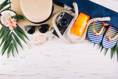 Yaz tatili konsepti. Plaj çantası ve aksesuarlar beyaz ahşap masada. Üst görünüm ve düz uzanma