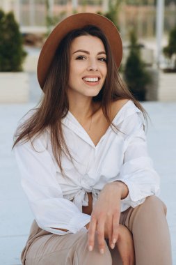 Şık bir kadın, sıcak bir yaz gününde gün batımında sahilde yürüyor.