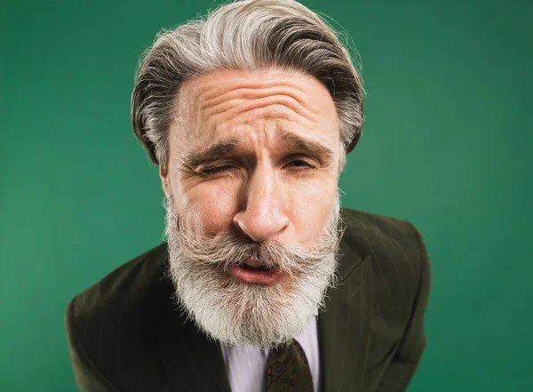 Funny bearded middle-aged man in khaki suit closeup on green background