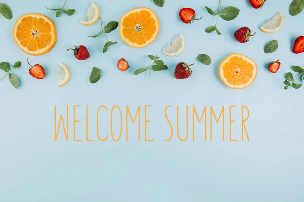 Welcome Summer concept and colorful flat lay. Pattern made of citrus fruits, leaves and strawberries on the blue wooden table