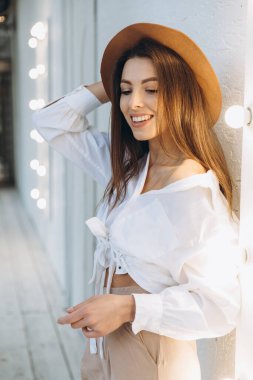 Şık bir kadın, sıcak bir yaz gününde gün batımında sahilde yürüyor.