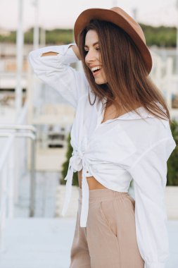 Mutlu, şık bir kadın, sıcak bir yaz gününde gün batımında sahilde yürüyor.