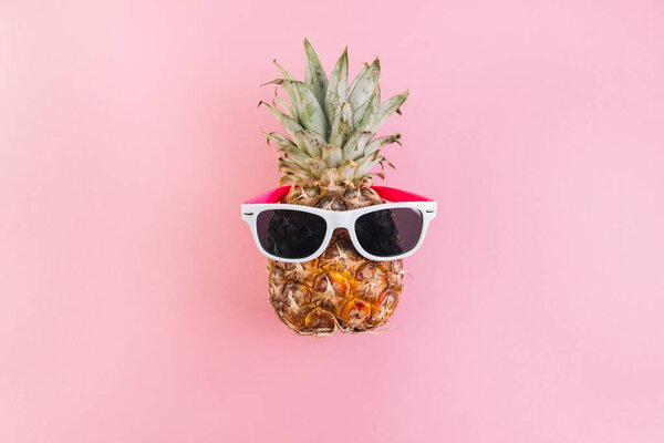 Summer concept. Cute and funny pineapple with sunglasses on pink background.
