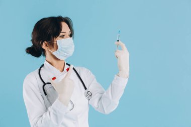 Steteskoplu kadın doktor, elinde enjeksiyon var, gri arka planda koronavirüse karşı panzehir. covid-2019 kavramı