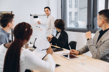 Bir grup çok kültürlü iş adamı, patronlarının konuşmasını dinliyor. Asyalı bir menajer ekibiyle konuşuyor.