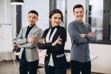 Başarılı bir iş kadını, çalışanları ile birlikte ofiste duruyor.