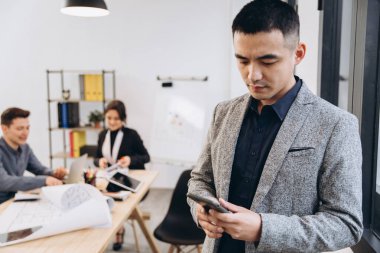 Modern çatı katında Asyalı bir işadamı cep telefonuyla konuşuyor.