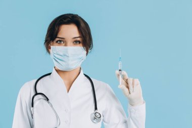 Steteskoplu kadın doktor, elinde enjeksiyon var, gri arka planda koronavirüse karşı panzehir. covid-2019 kavramı