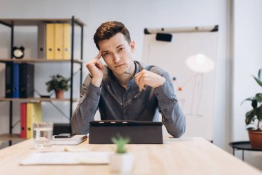Hasta ve yorgun hissediyorum. Hüsrana uğramış genç bir adam ofisteki iş yerinde otururken burnuna masaj yapıyor ve gözlerini kapalı tutuyor.