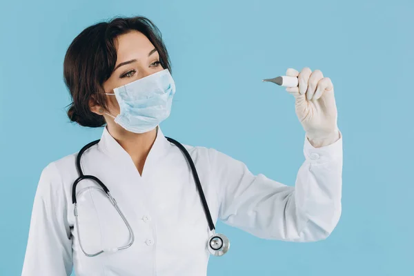 聴診器付きマスクの女性医師は電気温度計を保持しています Covid 19のコンセプト — ストック写真