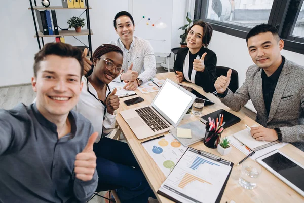 Multicultural group of professional business people making selfie in modern office