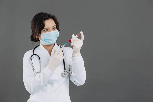 マスク注射を保持して聴診器を持つ女性医師 灰色の背景にコロナウイルスに対する解毒剤 Covid 2019のコンセプト — ストック写真
