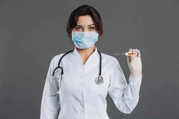 聴診器付きマスクの女性医師は電気温度計を保持しています Covid 19のコンセプト — ストック写真