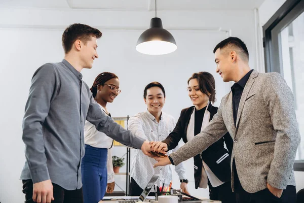 Multiracial euphoric business team people give high five at office table, happy excited diverse work group engaged in teambuilding celebrate corporate success win partnership power teamwork concept