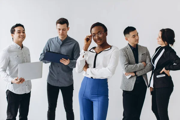 Group of multicultural young executive people standing and busy using smartphones for work in the office. Social media technology and online business with teenager lifestyle concept