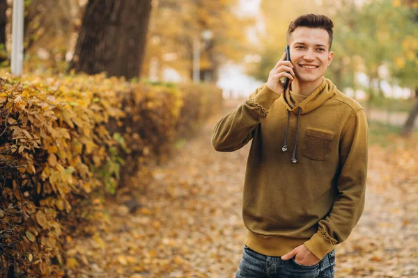 Portrét Pohledného Šťastného Chlapa Jak Usmívá Mluví Telefonu Podzimním Parku — Stock fotografie