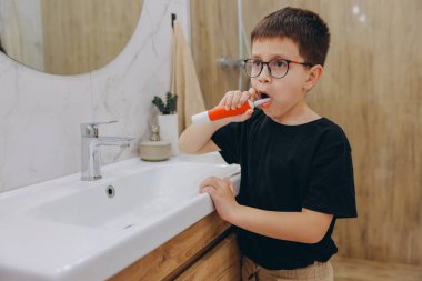 Young boy brushing his teeth with an electric toothbrush, promoting dental hygiene and healthy habits