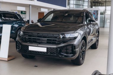 Sleek, gray SUV with black detailing takes center stage in a bright, modern car dealership, showcasing automotive excellence