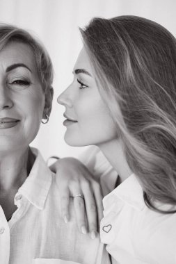 Daughter showing love and affection for her smiling mother in a tender black and white close up profile portrait
