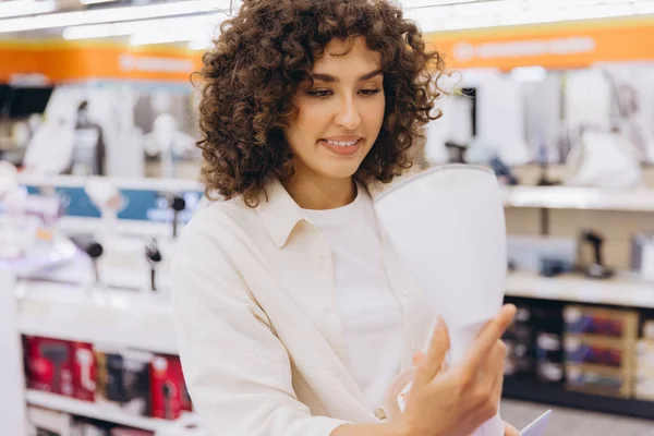Customer comparing various small appliances while shopping in an electronics store, evaluating options and considering purchase decisions
