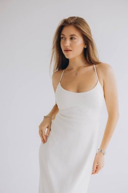 Fashion model posing wearing elegant white dress on seamless background, showcasing minimalist style and grace