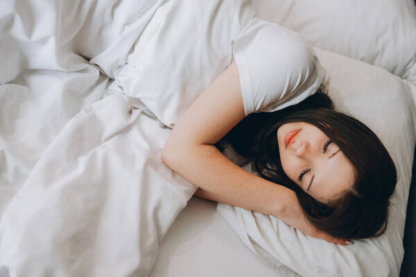 Young woman resting in bed enjoying a peaceful sleep, concept of relaxation and healthy sleep habits