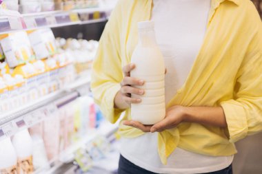 Customer selecting a fresh milk bottle in a supermarket, embracing healthy food choices and enjoying the grocery shopping experience