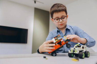 Renkli yapı taşlarıyla oynayan çocuk, rahat bir ev ortamında iyi motor beceriler ve yaratıcılık geliştiriyor.