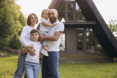 Smiling family embracing in front of their new home, enjoying the warmth of a sunny day while creating joyful memories together