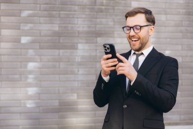 Happy businessman using mobile phone and wearing suit and tie