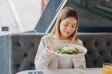 Happy customer smelling fresh salad with mozzarella in a restaurant, healthy food and lifestyle concept