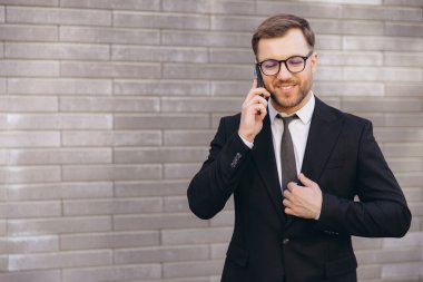 Businessman Wearing Suit and Tie Making a Phone Call in Front of Brick Wall