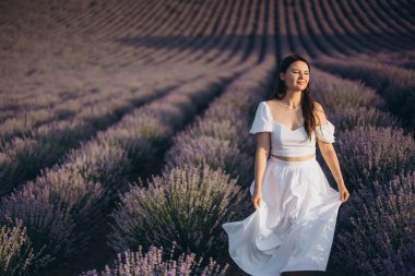Young woman embracing freedom while wandering through a stunning lavender field, surrounded by vibrant blooms at sunset's golden hour