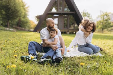 Happy family having fun during a picnic on a blanket in the garden of their modern a frame house