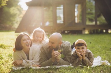 Happy family enjoying quality time together, lying on a cozy blanket in the backyard, laughing and bonding under the warm sunlight