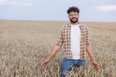 Young agronomist checking the growth of wheat plants in a golden field, ensuring a successful harvest