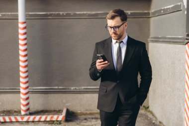 Businessman walking down the street and using his smartphone