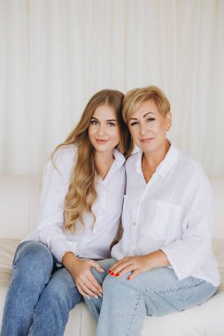 Mother and daughter sitting together on a white sofa, creating a heartwarming scene of family connection