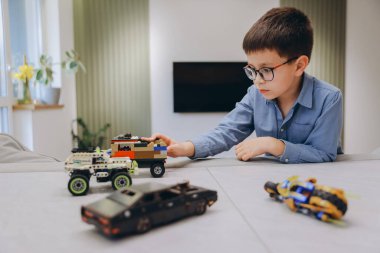 Child playing with plastic bricks cars, developing his imagination and creativity in a domestic environment