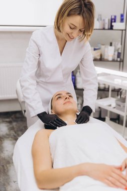 Beautician massaging a woman's neck with hydrating cream, enhancing relaxation and rejuvenation in a tranquil beauty salon environment