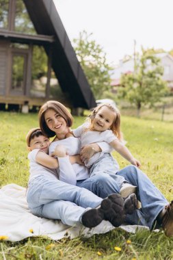 Mother and children hugging and smiling, enjoying a relaxing day outdoors in front of their modern a frame cabin