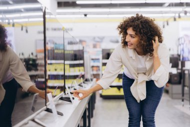 Customer comparing new television screens in consumer electronics store, choosing best display for home entertainment