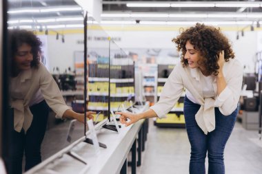 Customer comparing televisions in consumer electronics store, looking for best tv for home entertainment