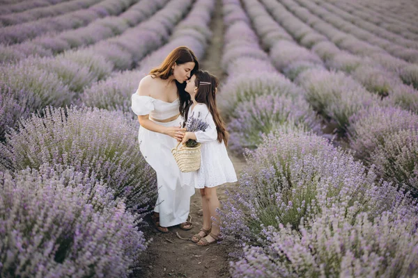 Mother and daughter sharing a tender moment in a stunning lavender field, joyfully holding a wicker basket filled with blossoms