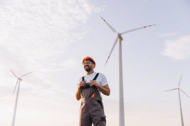Smiling Arab engineer working on a wind turbine, contributing to sustainable energy production and promoting clean power solutions