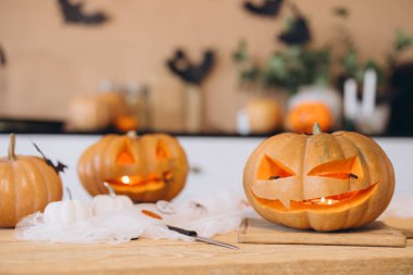 Cadılar Bayramı balkabakları oyulmuş yüzlerle ve ahşap bir masada mumlarla aydınlatılarak ürkütücü bir atmosfer yaratıyor.