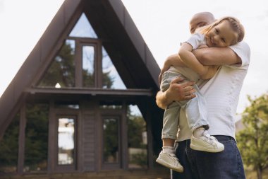 Father and daughter sharing a tender moment in front of their contemporary a frame home, celebrating Father's Day
