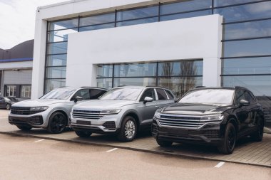 Shiny new suv cars parked in front of a modern car dealership building, ready to be purchased
