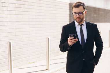 Businessman wearing suit and tie using smartphone while walking in a city street