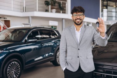 Salesperson holding car keys while standing in a showroom